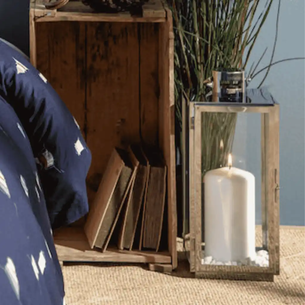 Orrefors Jernverk teräslyhty luomassa tunnelmaa makuuhuoneen lattialla, kynttilä palaa – elegantti henkilöstölahja