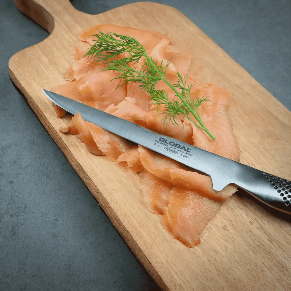 Joululahja idea. Global G-21 fileointiveitsi leikkaamassa graavilohta Global tammileikkuulaudalla