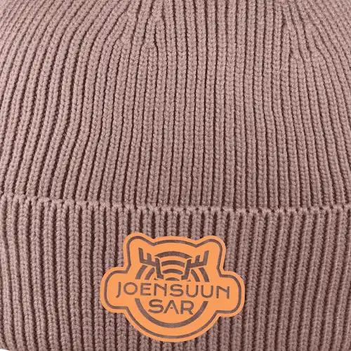 Pipo omalla logolla – laser-merkattu tekonahkamerkki ommeltuna pipoon, saatavilla myös kulta ja kromi.