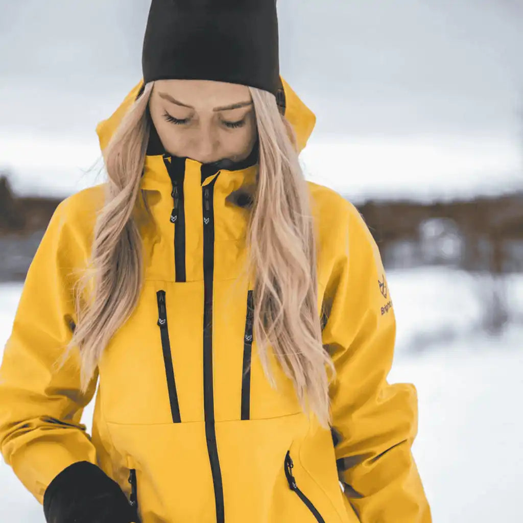 Nainen yllään keltainen Bright Equipment Enigma kuoritakki talvisessa ulkoilussa – lämmin ja suojaava joululahja