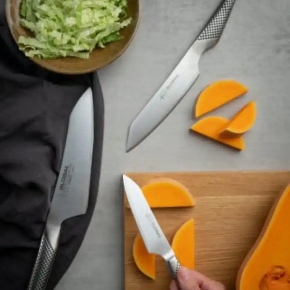 Global-veitsien tunnusomaiset teräskahvat hiekkatäytteellä lähikuvassa