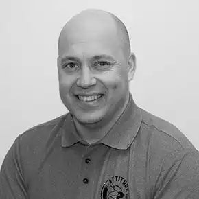 Mustavalkoinen ammatillinen potrettikuva henkilöstÀ, joka pitÀÀ yllÀÀn kauluspaitaa.