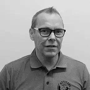 Mustavalkoinen muotokuva henkilöstÀ, joka pitÀÀ glasses ja polo-paitaa.