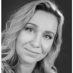 Mustavalkoinen potrettikuva, jossa on lempeÀ hymy ja laineikkaat vaaleat hiukset.