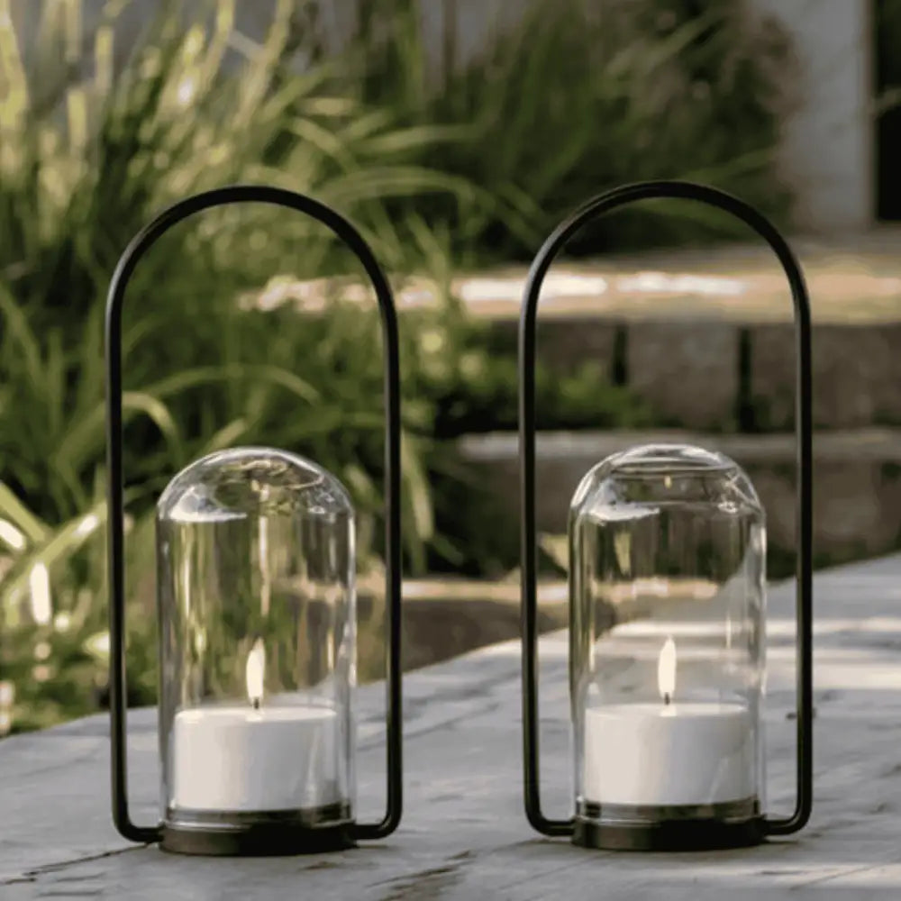 Kaksi Uyuni Outdoor Lyhty 2.0 -settiä luomassa tunnelmaa ulkona pöydällä – säänkestävä kesälahja