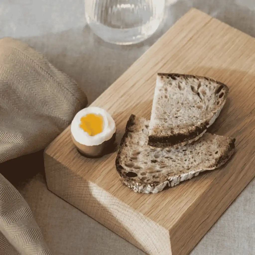 Pieni Ekta Living tammileikkuulauta aamiaiskäytössä leivän ja kananmunan kanssa – kaunis henkilöstölahja