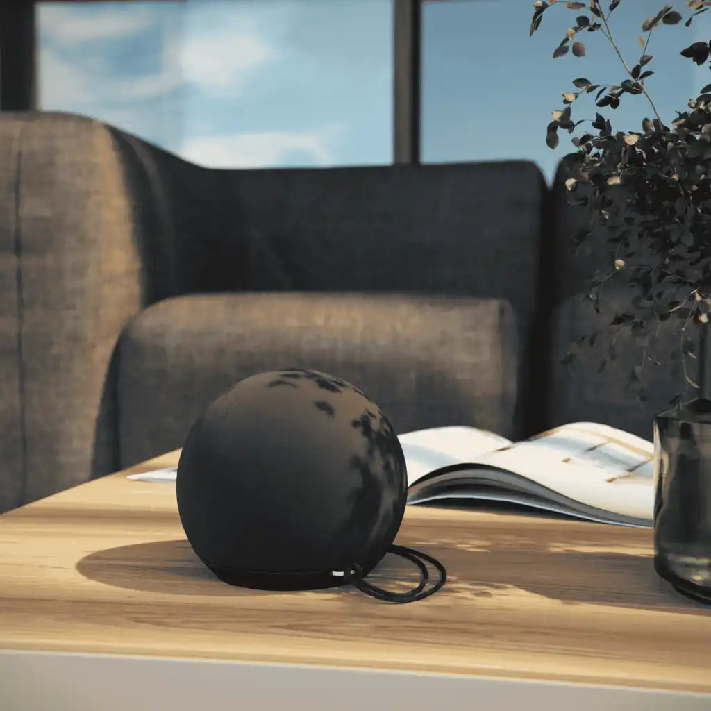 Musta SACKit Play Mini -kaiutin käytössä olohuoneen pöydällä – moderni joululahja työntekijöille