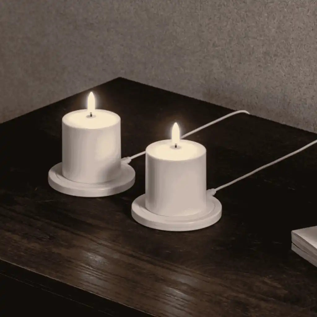 Kaksi Uyuni LED-pöytäkynttilää latautumassa omilla pyöreillä Uyuni-latausalustoillaan pöydällä